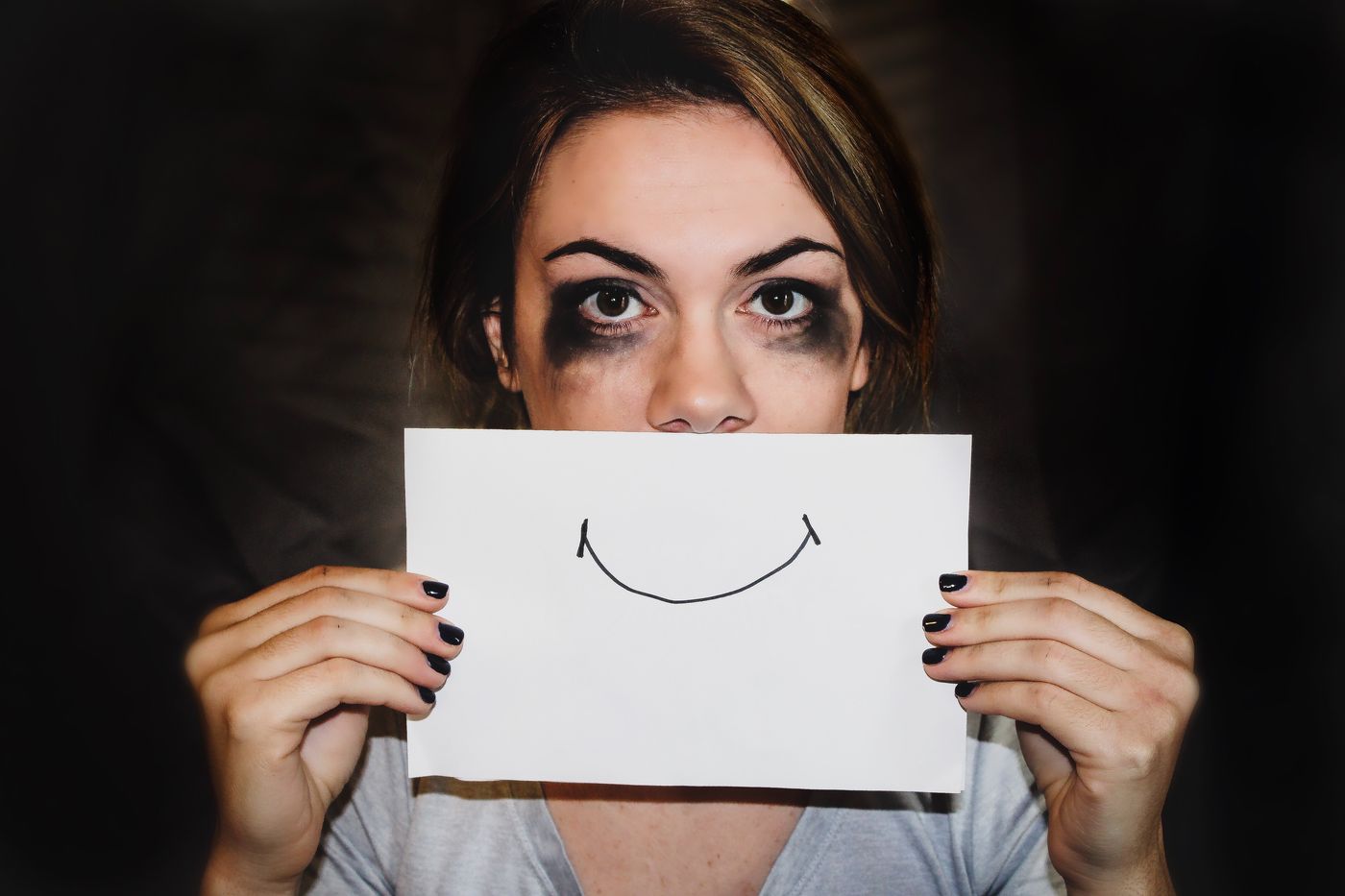 a woman holding a fake smile card in front of her head